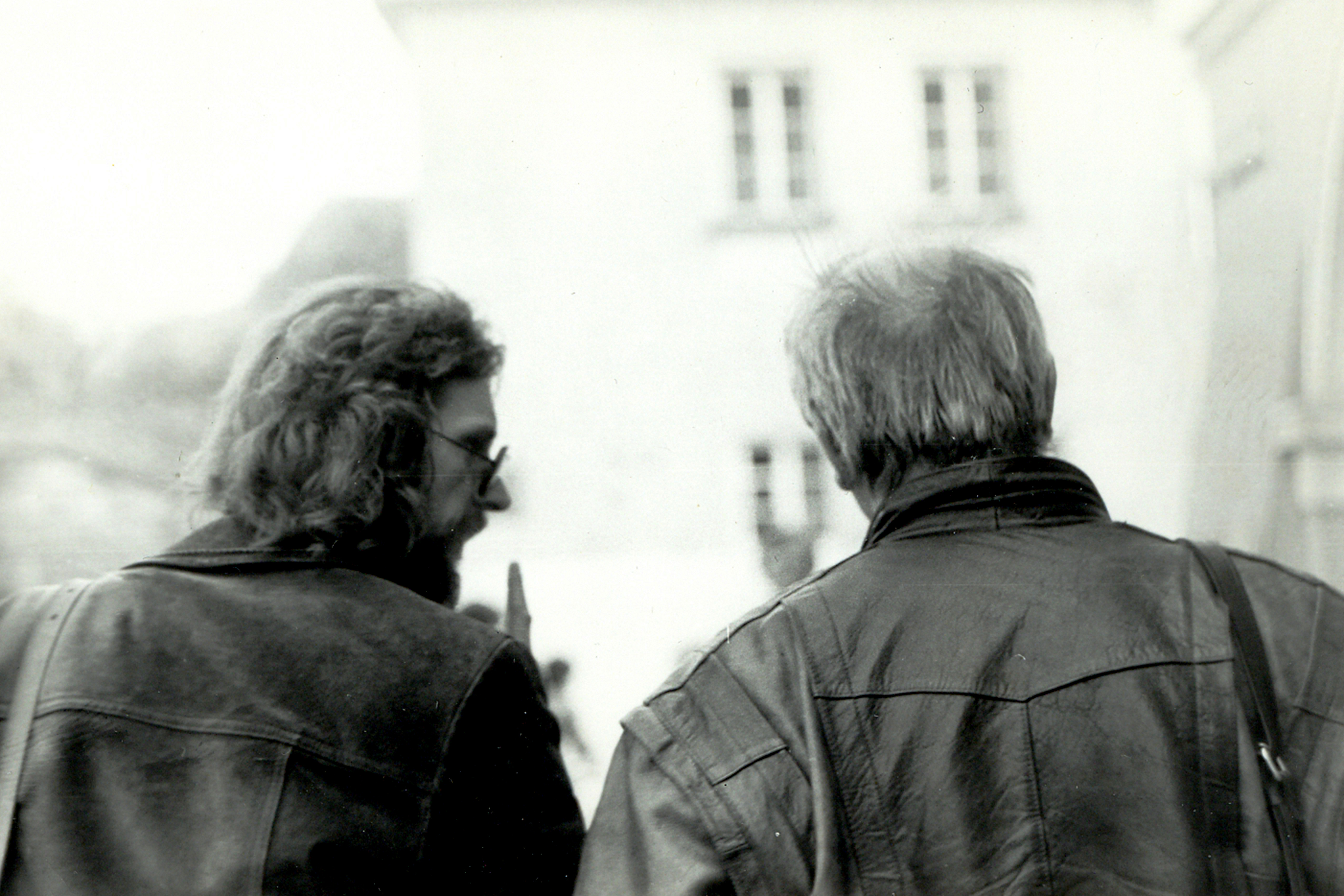 Czarno białe zdjęcie przedstawia dw&oacute;ch mężczyzn odwr&oacute;conych tyłem. 